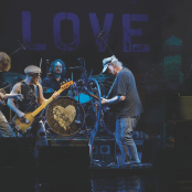 Neil Young and The Chrome Hearts playing their instruments 